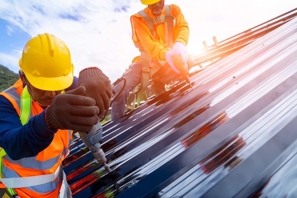Roofers installing a metal roof on a modern muskoka home